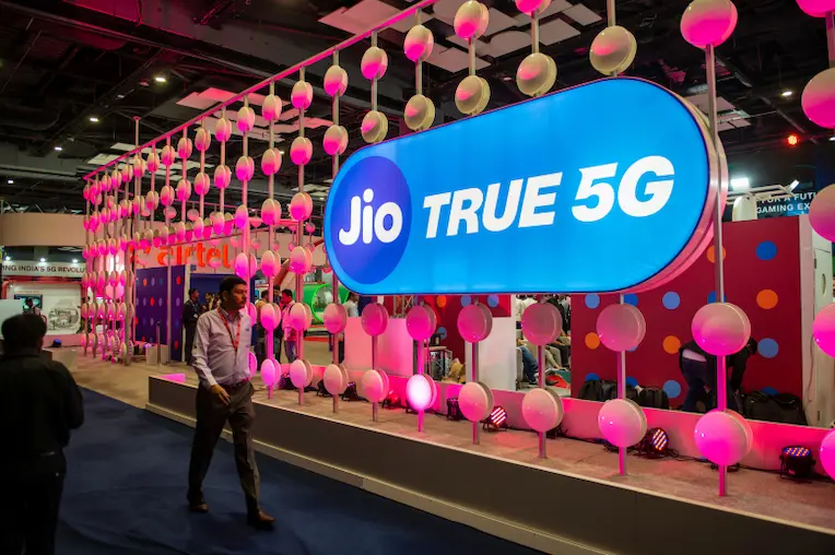 List of Jio Balance Enquiry Numbers Jio True 5G logo displayed at India Mobile Congress booth representing to check Jio USSD codes