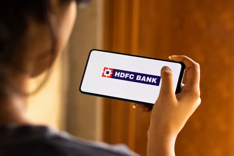 Women looking at HDFC mobile app displayed in mobile screen means HDFC Holidays