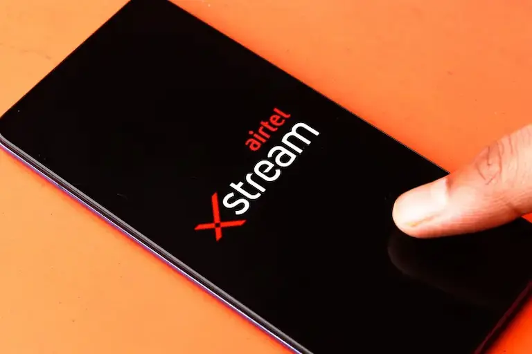  A close-up of a hand holding a smartphone featuring the Xstream logo clearly visible
