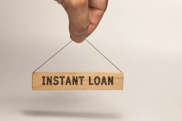 A hand holding a sign that reads "Instant Loan" against a clean white background, symbolizing quick financial assistance.
